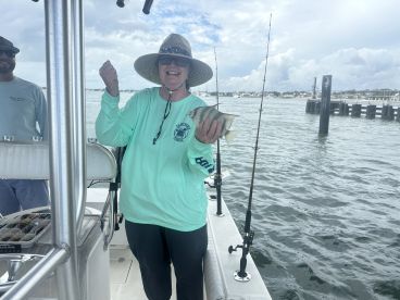 An excited angler holding a fish on a boat, showcasing a successful catch during a fishing trip.