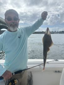 An angler proudly displays a caught fish while fishing from a boat, showcasing a successful day on the water.