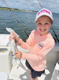 A young angler proudly displaying a caught shark while fishing on a boat, showcasing a fun day on the water.