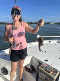 An angler proudly displaying a caught fish while fishing on a boat, showcasing a sunny day on the water.
