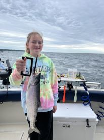 A young angler proudly displaying a freshly caught fish while fishing on a boat, showcasing a fun day on the water.
