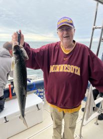 An enthusiastic angler proudly displaying a large Walleye while fishing on a boat, showcasing a successful day on the water.