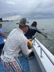 Anglers actively reeling in a catch while fishing on a boat, showcasing the excitement of the sport in a coastal environment.