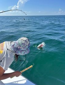 An angler actively reeling in a fish while fishing in open waters, showcasing the excitement of the catch.