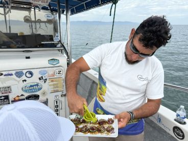A crew member preparing a dish on a fishing boat, showcasing the culinary experience available during the trip.