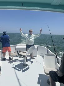 A group of anglers enjoying a day on the water, with one person playfully posing on the boat's deck.