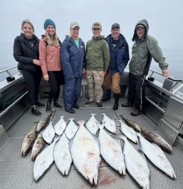 A group of anglers proudly displaying their catch of Halibut and Rockfish on the deck of a fishing boat, showcasing a successful day on the water.