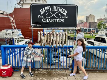 Two young anglers proudly posing with a display of freshly caught fish at the dock, showcasing their successful fishing trip on Lake Superior.
