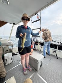 An angler proudly displaying a freshly caught Walleye aboard a fishing boat, showcasing a successful day on the water.