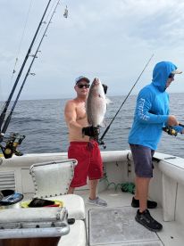 Angler proudly displaying a large Snapper while fishing on a charter boat in open waters.