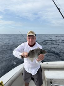 An angler proudly displaying a caught fish while aboard a fishing boat in open waters.