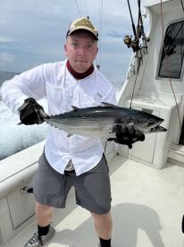 Angler proudly displaying a large Blackfin Tuna while aboard a sportfishing boat in open waters.