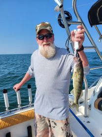 An angler proudly displaying a Walleye while fishing on a boat in clear waters.