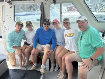 A group of young adults enjoying their time inside a fishing boat, showcasing a relaxed atmosphere before heading out for a fishing adventure.