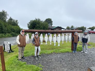 Group of anglers proudly displaying their catch of Halibut on a catch board after a successful fishing trip.