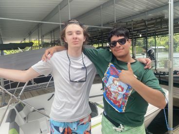 Two young men posing together on a boat dock, showcasing a casual fishing outing atmosphere.