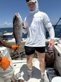 A young angler proudly displaying a large fish on a boat during a deep-sea fishing trip.