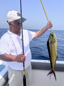 An angler proudly displaying a vibrant Mahi Mahi while fishing offshore, showcasing a successful day on the water.