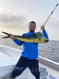 Angler proudly displaying a vibrant Mahi Mahi while fishing offshore, showcasing the excitement of a successful catch.