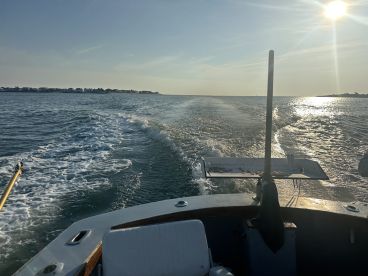 A scenic view from the boat, showcasing the wake and shoreline during a sunset cruise, ideal for fishing enthusiasts.