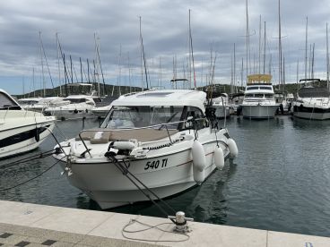 A sleek motorboat docked in a marina, surrounded by various other vessels, showcasing a tranquil boating environment.