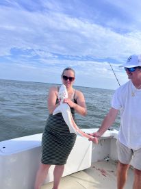 An angler proudly displaying a caught shark while fishing on a boat, showcasing a sunny day on the water.