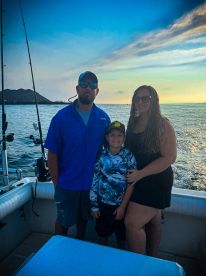 A family poses together on a fishing boat during sunset, showcasing a relaxed atmosphere on the water.