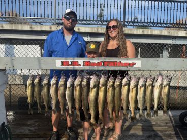 A family proudly displays their catch of Walleye on a catch board after a successful fishing trip.