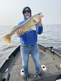 A young angler proudly displaying a Walleye while fishing on a boat, showcasing the excitement of a successful catch.