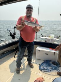 An angler proudly displaying a caught fish aboard a boat, enjoying a day of fishing on the water.