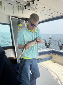 A young angler proudly displaying a caught fish aboard a fishing boat, showcasing the excitement of a successful fishing trip.