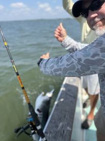 Angler reeling in a fish while fishing from a boat, showcasing the excitement of the catch in a coastal fishing environment.