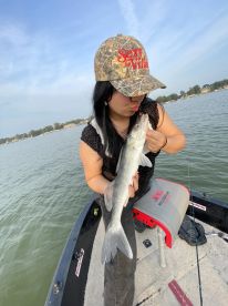 An angler proudly holding a freshly caught Walleye while fishing from a small boat on a calm lake.