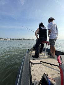 Two anglers casting lines from a small boat on a calm waterway, enjoying a day of fishing.