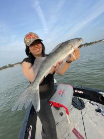 Angler proudly displaying a large Walleye while fishing from a boat on a calm lake.