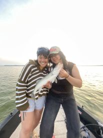 Two anglers proudly displaying a freshly caught Walleye while enjoying a fishing trip on a boat.