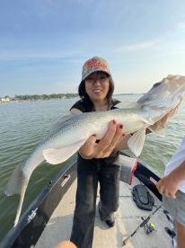A proud angler holding a large Walleye while fishing from a boat, showcasing a successful catch on a sunny day.