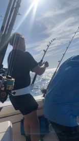 Angler actively reeling in a catch while fishing on a sunny day, showcasing the excitement of deep-sea fishing.