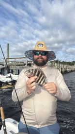 Angler proudly displaying a Sheepshead caught while fishing near a dock, showcasing a sunny day on the water.