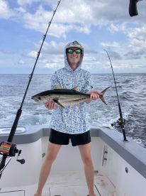 Young angler proudly holding a large fish while fishing offshore, showcasing a beautiful day on the water.