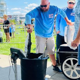 Anglers weighing in their catch at a fishing tournament, showcasing large fish in a competitive setting.