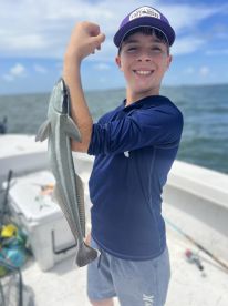 A young angler proudly displaying a caught fish while on a fishing trip, showcasing the excitement of fishing in open waters.