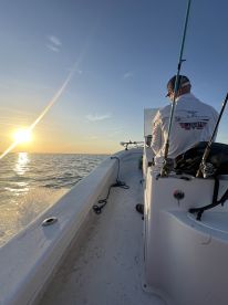 A serene sunset view from inside a fishing boat, showcasing the helm and seating area as the angler prepares for a day on the water.