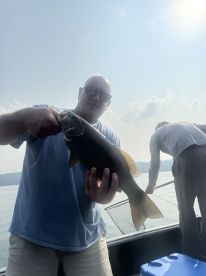 An angler proudly displaying a large Smallmouth Bass while fishing on a serene lake.