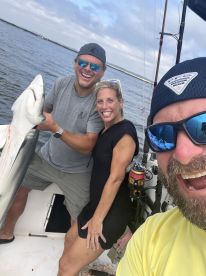 Two anglers proudly displaying a large shark while enjoying a day of fishing on the water.