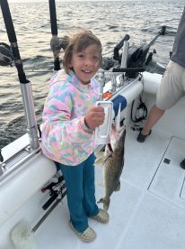 A young angler joyfully holding a freshly caught Walleye while fishing on a boat, showcasing the excitement of a family fishing trip.