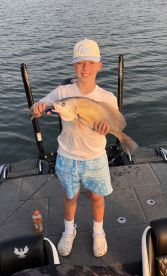 Young angler proudly displaying a large Snapper while fishing on a boat, showcasing a successful day on the water.