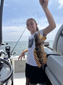 A young angler proudly displaying a caught fish while aboard a boat, enjoying a day of fishing on the water.