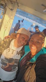 Two friends enjoying their time on a fishing charter boat, capturing a moment together with the scenic ocean in the background.