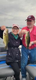 Two anglers proudly displaying their catch of Largemouth Bass while enjoying a day on the water.